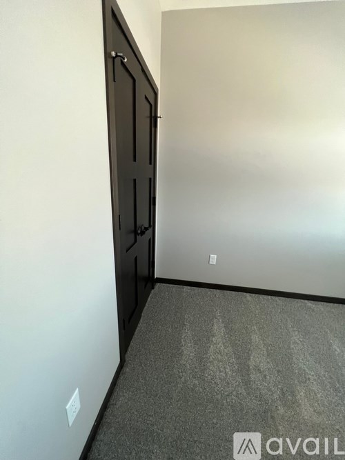 A room with a black door and a grey carpet.