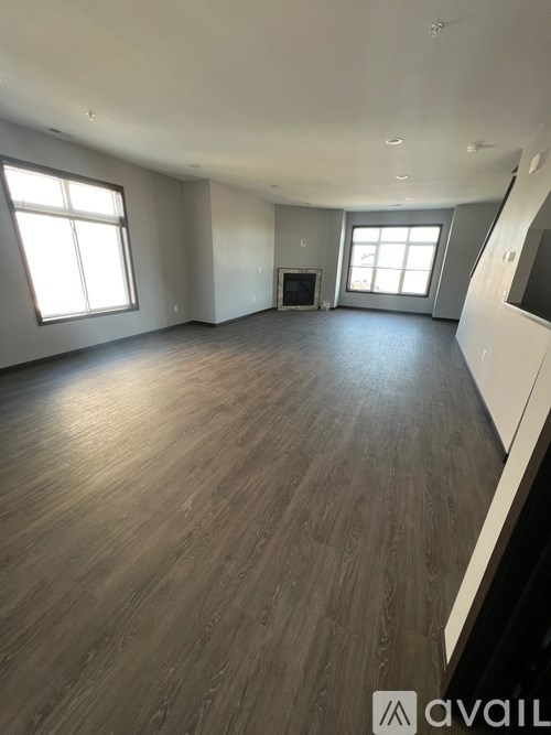 A spacious room with wooden flooring and a fireplace.