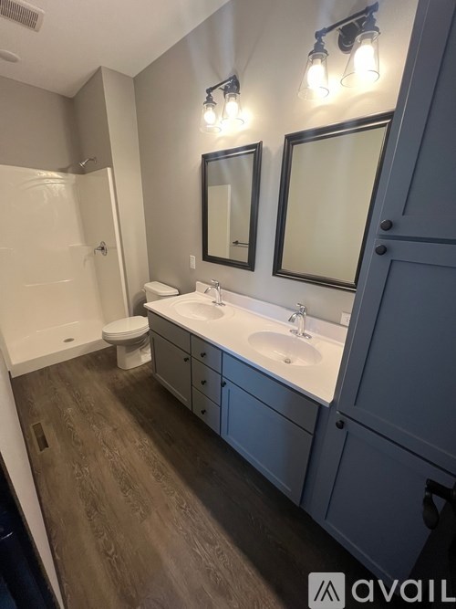 A bathroom with a toilet, sink, and mirrors.