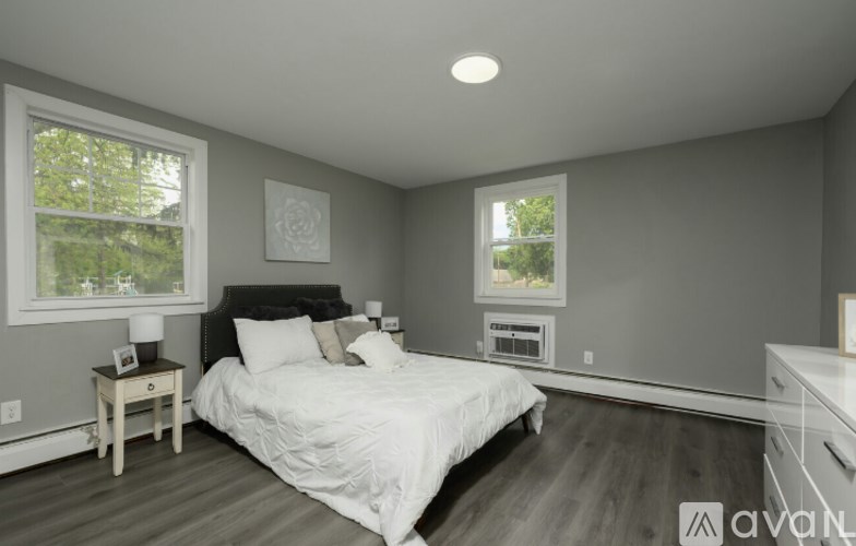 A bedroom with a large bed, a nightstand with a lamp, and a window with a view of trees.