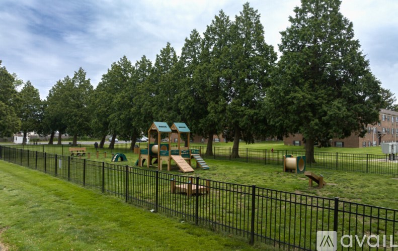A playground with a green slide and a black fence.