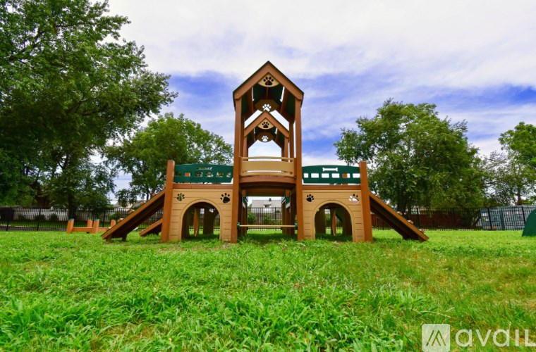 A wooden playground structure with a green sign that reads "Kids Playground" in front of a fence.
