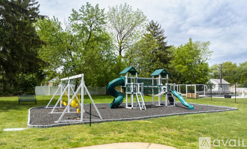 A playground with a green slide and a yellow ball on a grey surface.