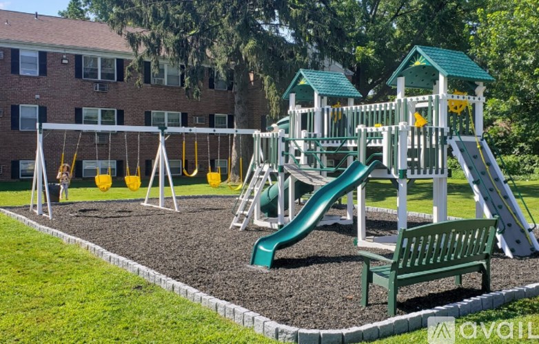 A playground with a green slide and a green bench.