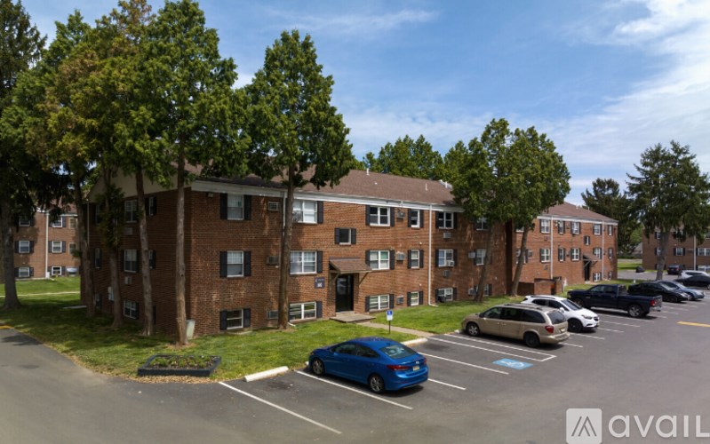 A blue car is parked in a parking lot in front of a brick building.
