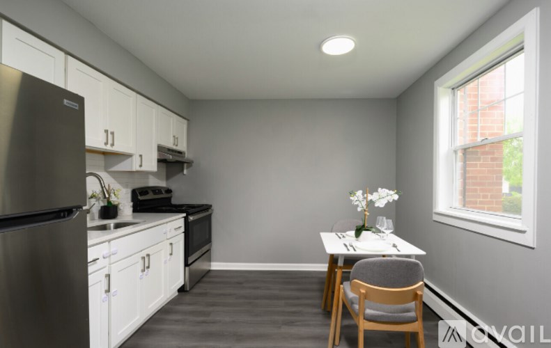 A kitchen with a refrigerator, stove, and a dining table with chairs.