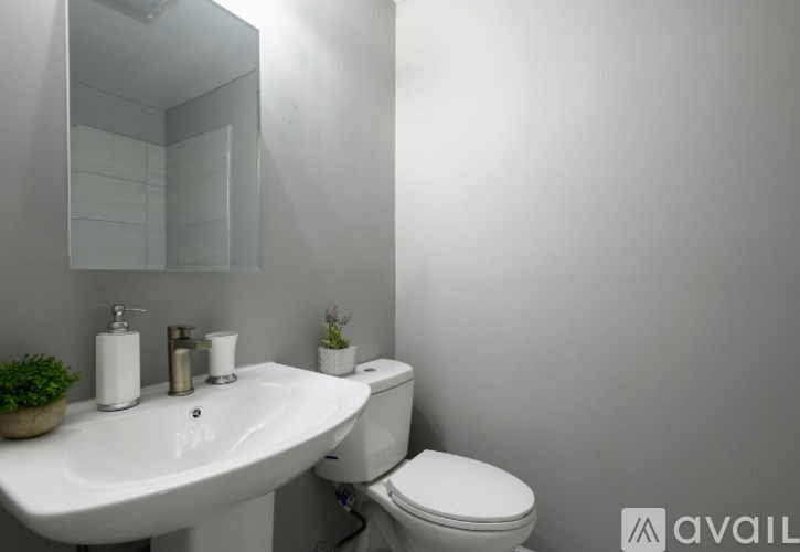 A white sink with a mirror above it and a toilet behind it.