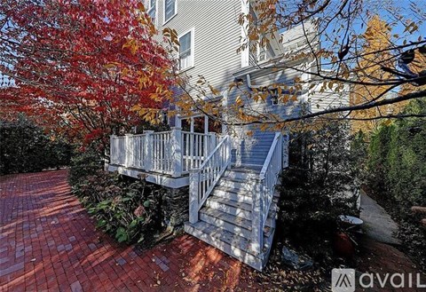 A house with a deck and a tree with red leaves.