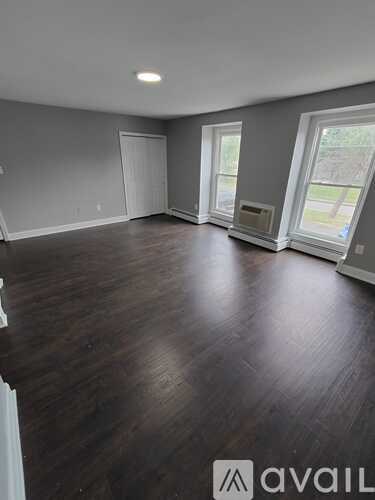 A room with wooden flooring and a window on the right side.