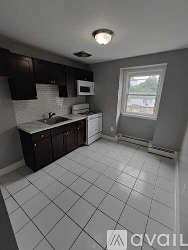 A kitchen with white tiled floors and dark brown cabinets.