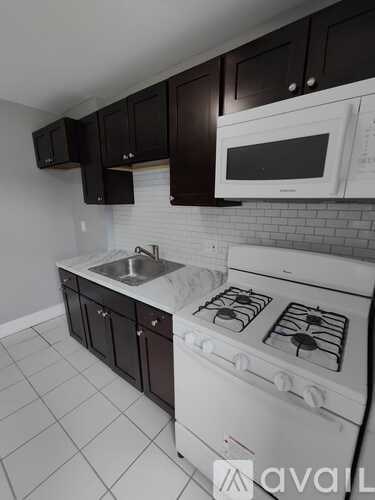 A kitchen with a white stove top oven and black cabinets.