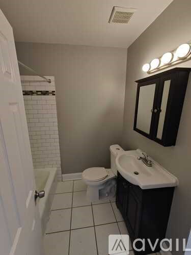 A bathroom with a toilet, sink, and mirror.