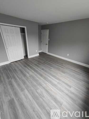 A room with grey walls and wooden flooring with two doors.