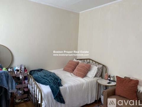 A bedroom with a bed, a side table, and a mirror.