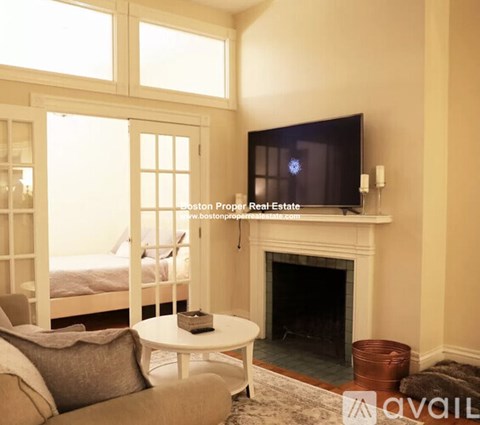 A living room with a fireplace and a television mounted above it.