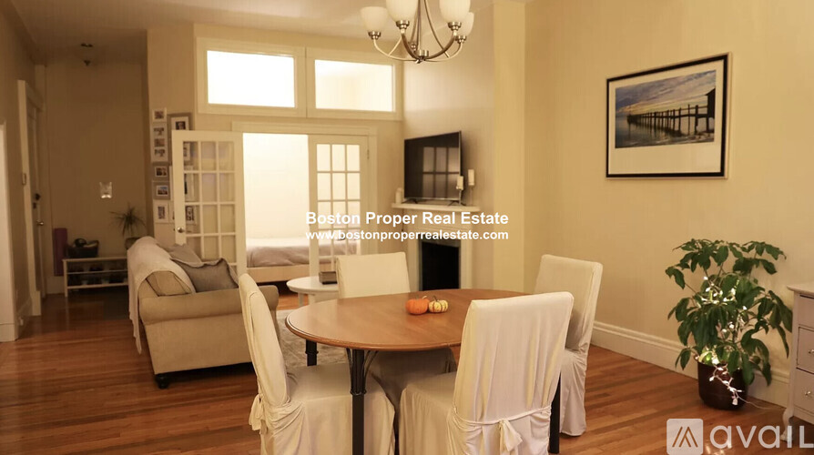 A dining room with a table set for two and a chandelier hanging from the ceiling.