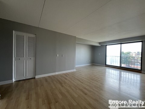A room with wooden flooring and a sliding glass door.