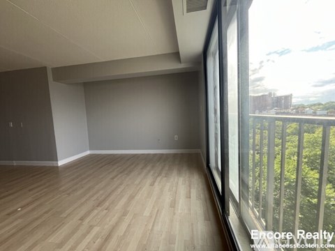 Empty room with wooden flooring and a view of the outdoors through a window.