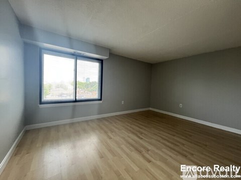A room with wooden flooring and a window showing a view of the outside.