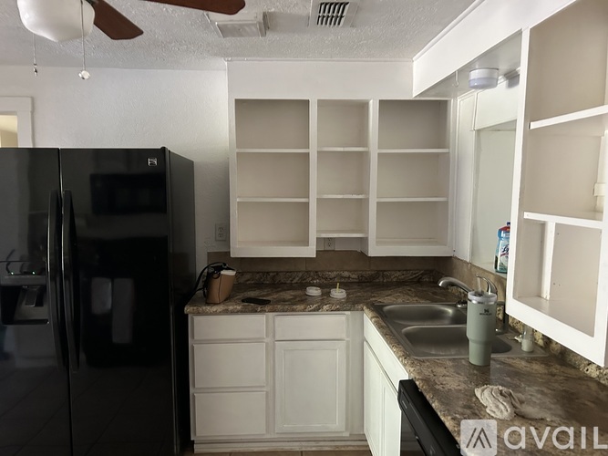 A kitchen with a black fridge and white cabinets.