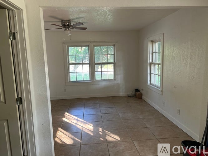 A room with a ceiling fan and two windows.