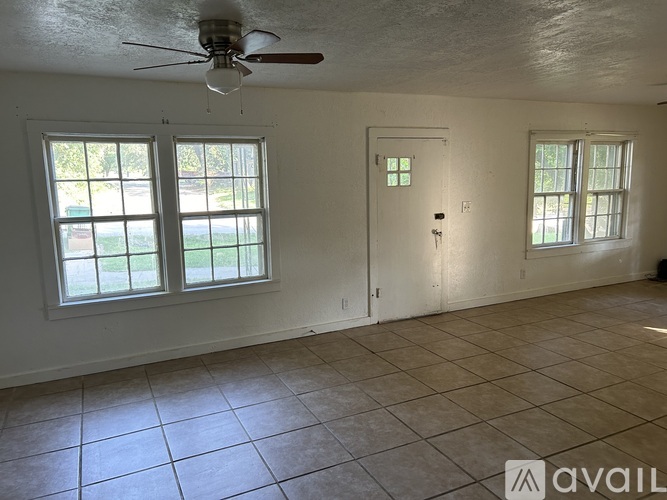 A room with a ceiling fan and two windows.