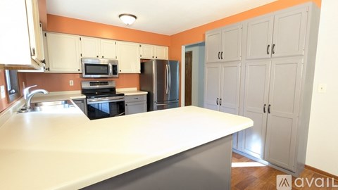 A kitchen with a white counter and orange walls.