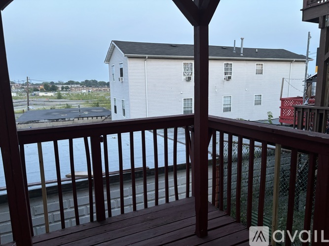 A white house is seen from a deck with a view of the water.