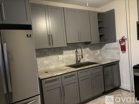 A kitchen with grey cabinets and a marble countertop.