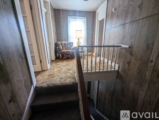 A room with wooden walls and a staircase leading to the second floor.