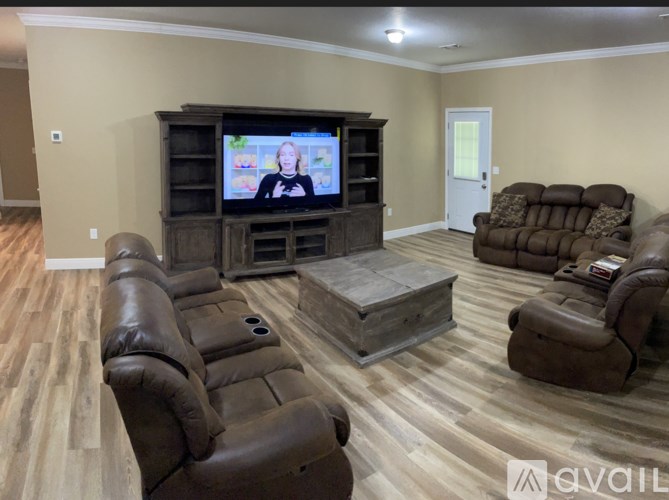 A living room with brown leather furniture and a wooden entertainment center.