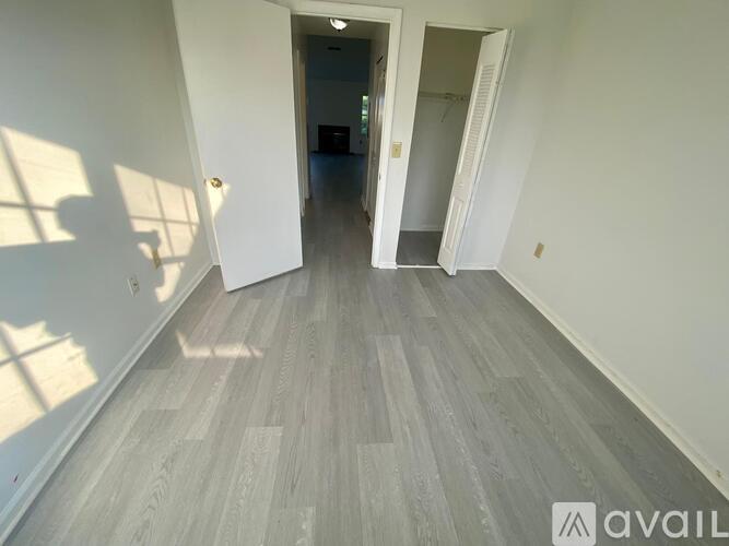 A long hallway with a wooden floor and white walls.
