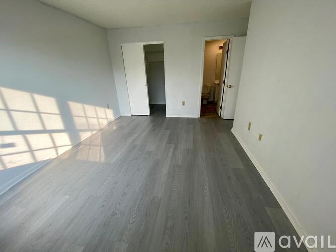 A spacious room with wooden flooring and two doors leading to other rooms.