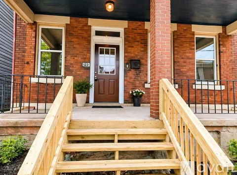 A red brick house with a wooden staircase leading to the front door.