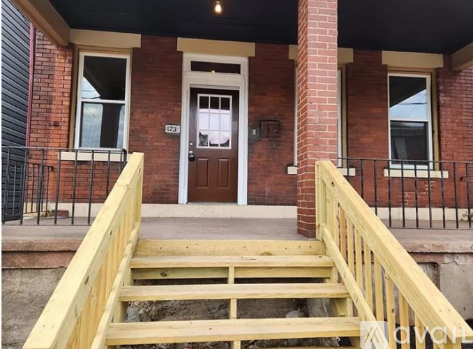 A red brick house with a wooden staircase leading to the front door.