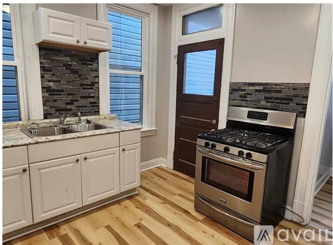 A kitchen with wooden floors, a stove, and a sink.