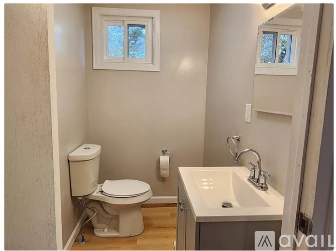 A small bathroom with a toilet, sink, and mirror.