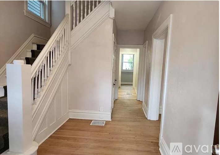 A long hallway with a staircase on the left and a door on the right.