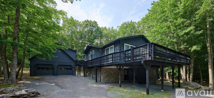 A modern house with a balcony is surrounded by trees.