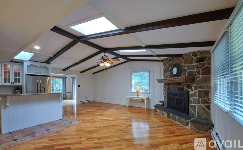 A spacious room with wooden floors and a stone fireplace.