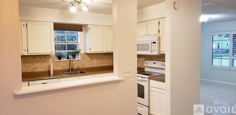 A kitchen with white cabinets and a window.