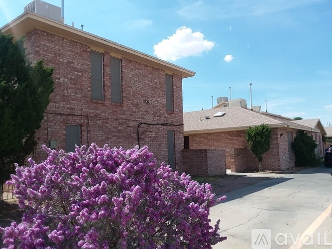 A house with a brick facade and a large bush of purple flowers in front.