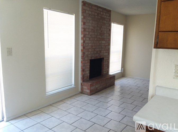 A room with a brick fireplace and tiled flooring.