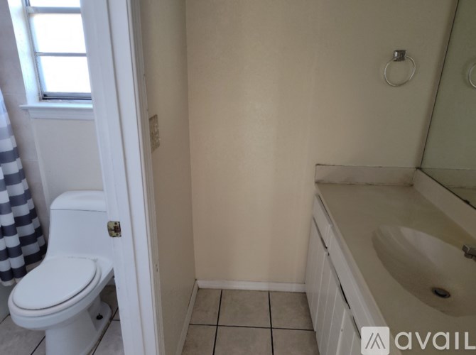 A bathroom with a toilet, sink, and a window.