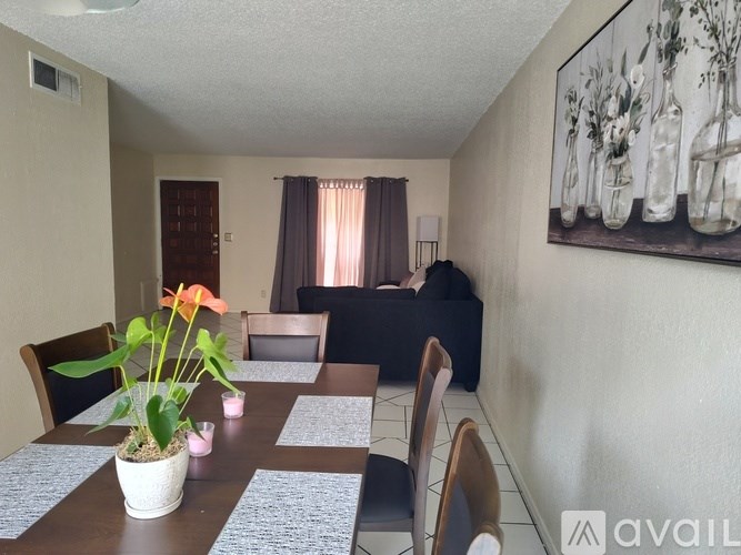 A dining room with a table set for six and a painting on the wall.