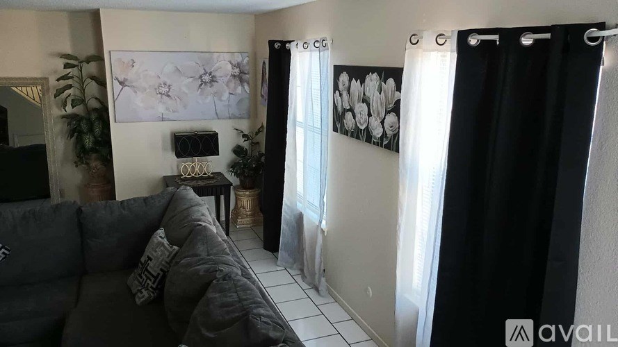 A black couch with a pink pillow and a pink blanket sits in a room with a dining table and chairs.