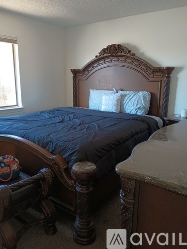 A bed with a brown headboard and a blue comforter.