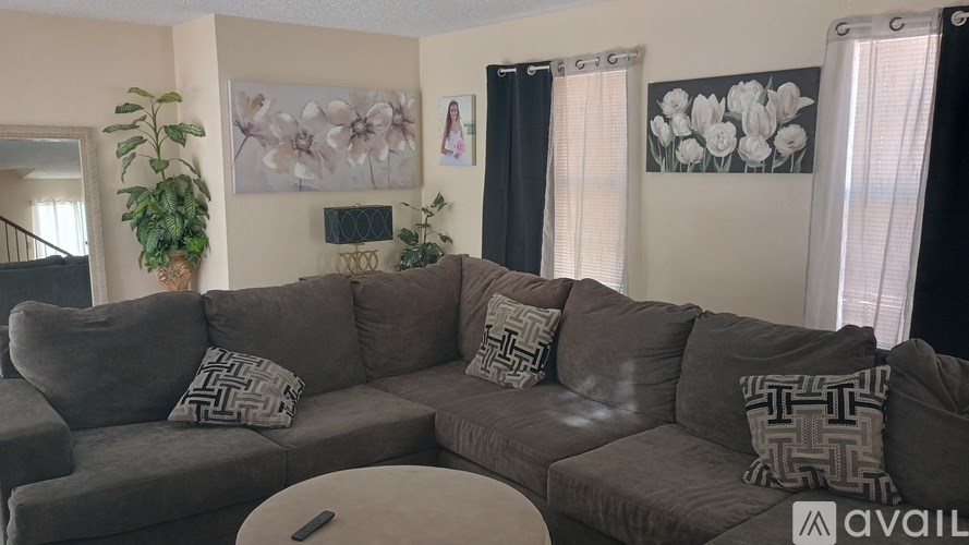 A grey sectional sofa with a round ottoman in front of it.