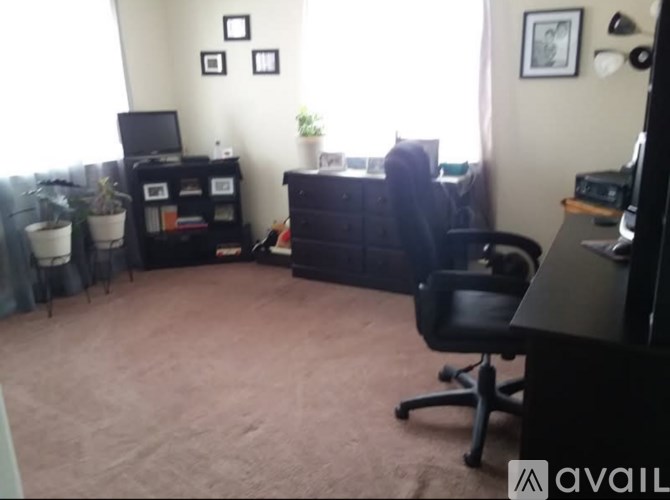 A room with a black chair and a black desk with a computer on it.