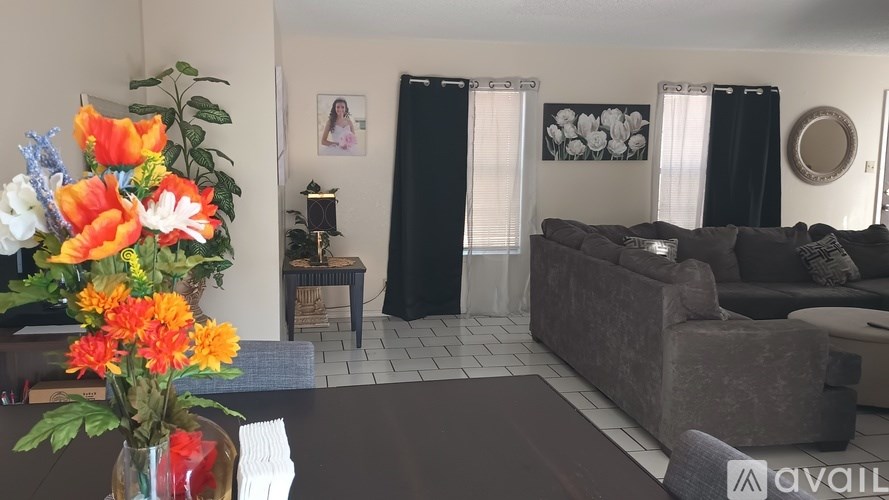 A living room with a brown couch and a vase of flowers on the table.